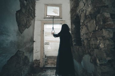 Ghost in abandoned, haunted house. Horror scene of scary spirit of a woman and rope with a noose, halloween concept.