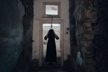 Ghost in abandoned, haunted house. Horror scene of scary spirit of a woman and rope with a noose, halloween concept.