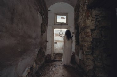 Ghost in abandoned, haunted house. Horror scene of scary spirit of a woman and rope with a noose, halloween concept.