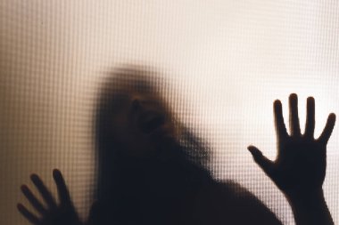 Horror ghost woman behind the matte glass. Halloween festival concept.