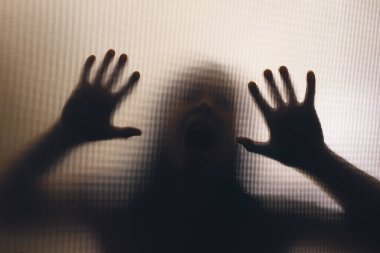 Horror ghost woman behind the matte glass. Halloween festival concept.