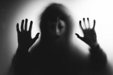 Horror ghost woman behind the matte glass. Halloween festival concept.