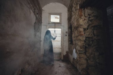 Ghost in abandoned, haunted house. Horror scene of scary spirit of a woman and rope with a noose, halloween concept.