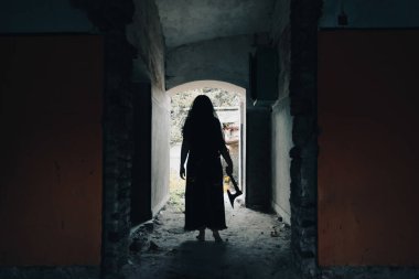 Terk edilmiş, perili bir evde hayalet. Eski balta ve cadılar bayramı konseptini tutan ürkütücü siluet sahnesi.