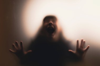 Matte camının arkasında korkmuş, çığlık atan bir kız. Cadılar Bayramı festivali.