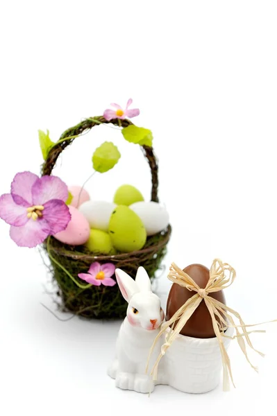 Coloridos huevos de Pascua pintados en cesta y taza de huevo con huevo de chocolate — Foto de Stock