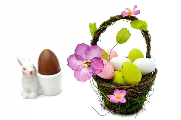 Colorful painted easter eggs in basket and egg cup with chocolate egg — Stock Photo, Image