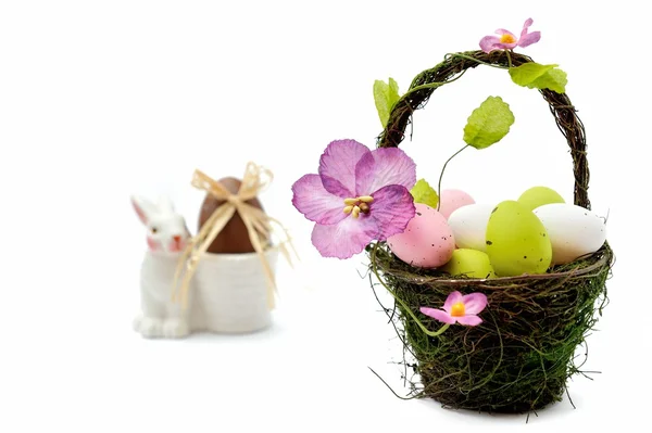 Colorful painted easter eggs in basket and egg cup with chocolate egg — Stock Photo, Image