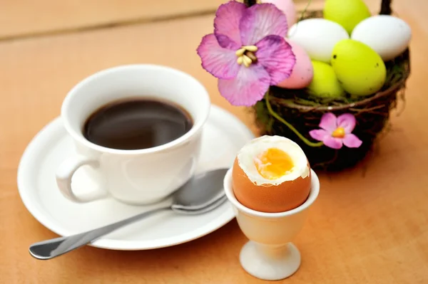 Πολύχρωμα βαμμένα αυγά του Πάσχα στο καλάθι, ένα φλιτζάνι μαύρο καφέ και αυγοθήκη — Φωτογραφία Αρχείου