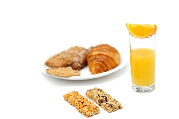 Pan de desayuno en plato blanco, barras de avena y un vaso de jugo de naranja sobre fondo blanco — Foto de Stock