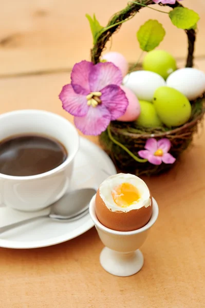 Барвисті розмальовані великодні яйця в кошику, чашка чорної кави та яєчна чашка Стокова Картинка