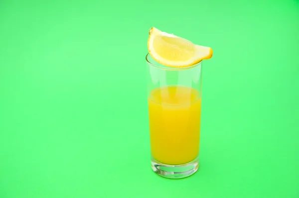 Склянка апельсинового соку на зеленому фоні Стокове Зображення