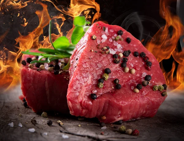 Raw beef steaks with fire flames — Stock Photo, Image