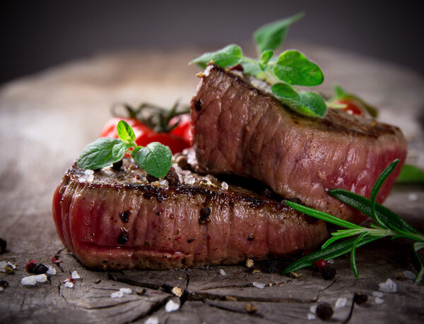 Grilled bbq steaks on wooden background