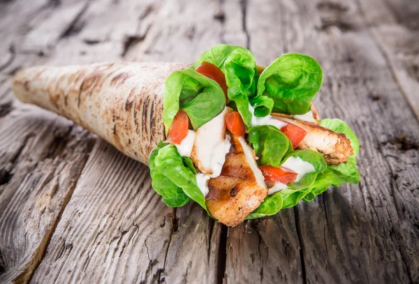 Kip segmenten in een tortilla wrap op hout. — Stockfoto