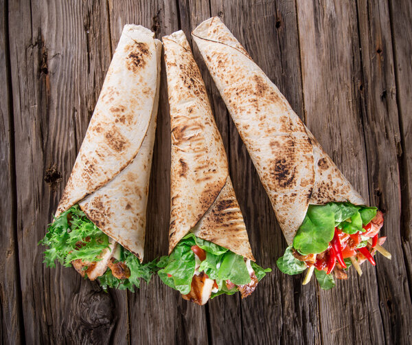 Chicken strips in a Tortilla Wrap on wood.