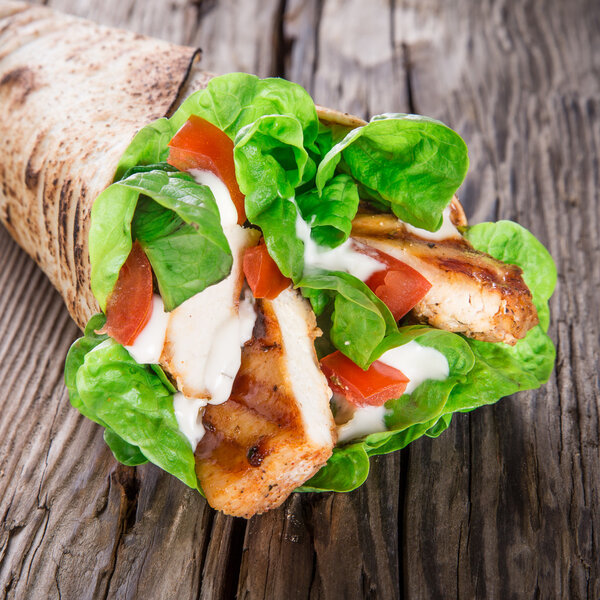 Chicken strips in a Tortilla Wrap on wood.