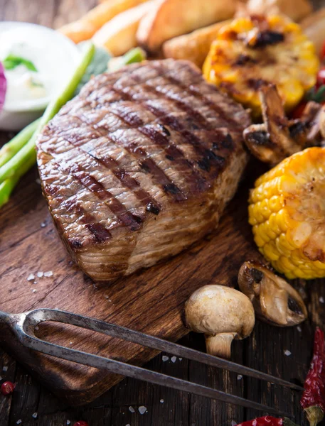 Beef steak on wooden table — Stock Photo, Image