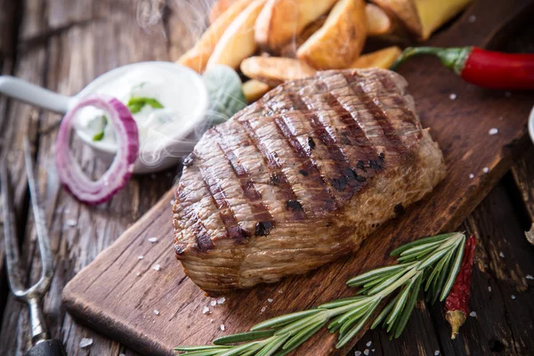 Beef steak on wooden table — Stock Photo, Image