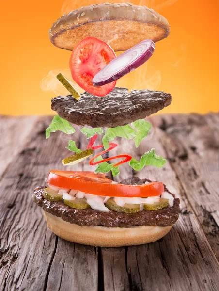Deliciosa hamburguesa con ingredientes voladores —  Fotos de Stock