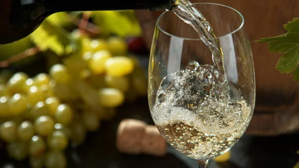 Pouring white wine, black stone background. — Stock Photo, Image