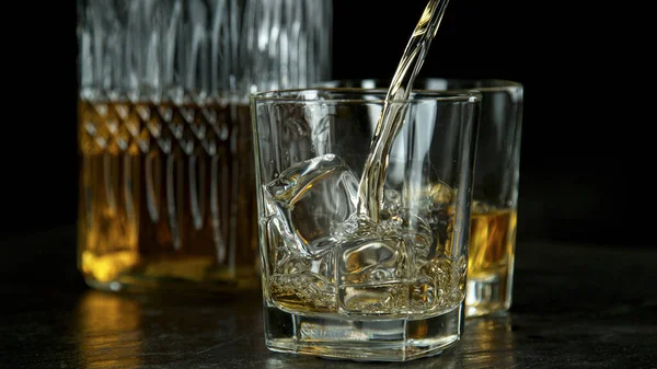Verser du whisky dans du verre sur une table en pierre noire — Photo
