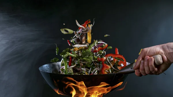 Freeze Motion of Wok Pan and Flying Ingredients in the Air. — Foto de Stock