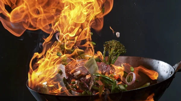 Freeze Motion of Wok Pan and Flying Ingredients in the Air. — Foto de Stock