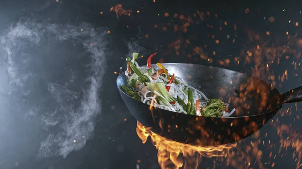 Freeze Motion of Wok Pan and Flying Ingredients in the Air. — Foto de Stock