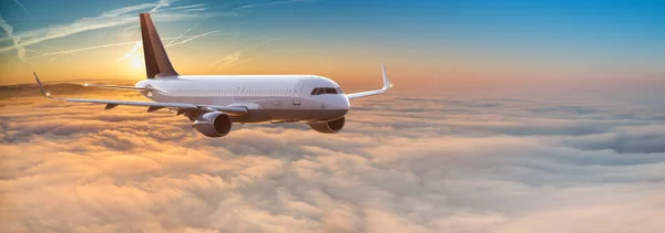 夕阳西下在云上飞行的商业客机. — 图库照片