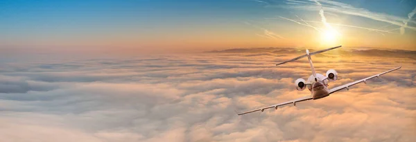 Private jet plane flying above clouds in beautiful sunset. — Stock Photo, Image