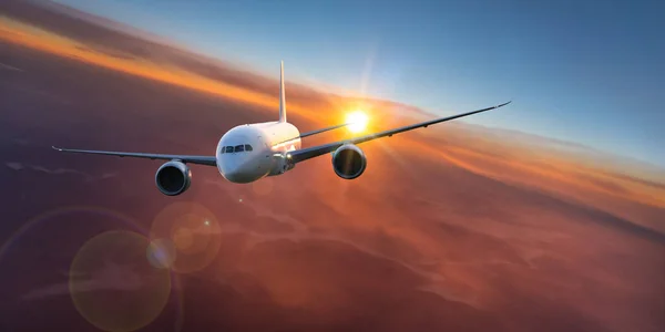 Pasajeros avión comercial volando por encima de las nubes en la luz del atardecer. — Foto de Stock