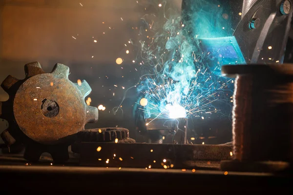 Welder welding a piece of iron tool — Stock Photo, Image