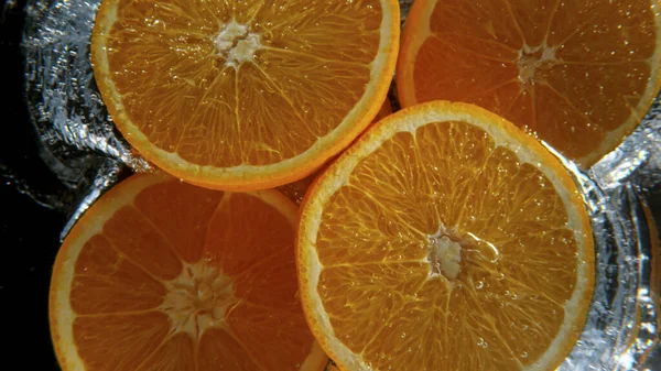 Świeże pomarańcze wpadające do wody, zamrożenie ruchu. — Zdjęcie stockowe