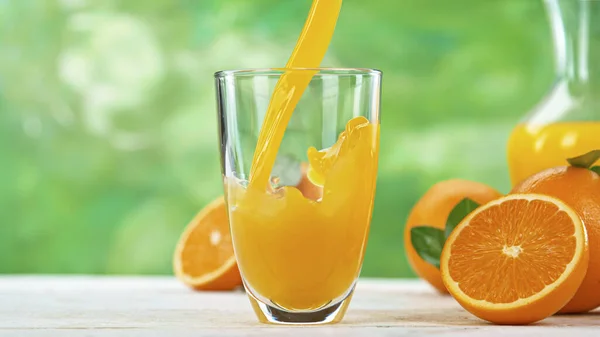 Suco de laranja fresco sendo derramado em um copo — Fotografia de Stock