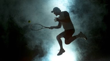 Zıplayan Oyuncu Arka planda Atmosferik Dumanla Tenis Topuna Vuruyor