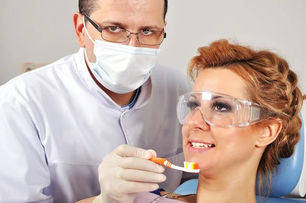 Diş hekimi diş fırçası gösterir — Stok fotoğraf