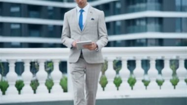 Modern Şehir Arkaplanı 'nda İşadamı Dijital Tablet Bilgisayarla Yürüyor. İş ve İletişim Teknolojisi Konsepti.