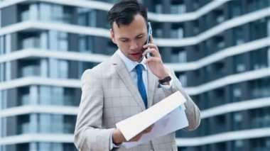 Finansal danışman akıllı telefondan konuşuyor ve iş sözleşmesini elinde tutuyor. İş ve Bilgi Teknolojisi Konsepti.