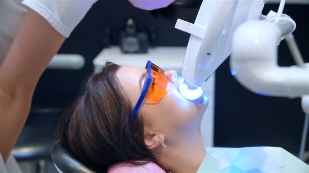 先生はクリニックで女性患者と歯のホワイトニング手順を見ています 歯と歯のホワイトニングコンセプト — ストック動画