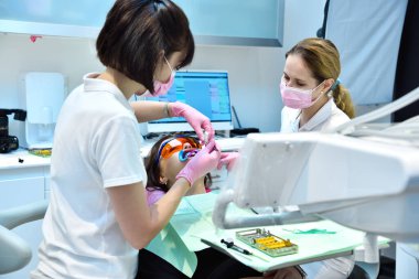 Diş sağlığı kliniğinde diş beyazlatma prosedürü için koruyucu gözlüklü ve retraktörlü kadın hasta. Diş ve diş beyazlatma kavramı.