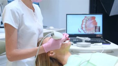 Modern Klinikte diş taraması için 3 boyutlu diş içi tarayıcı kullanan bir diş hekimi. Modern Diş ve Sağlık Hizmetleri Konsepti. Yavaş Hareket Efekti.