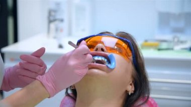 Kadın diş hekimi hastayı diş beyazlatma prosedürüne hazırlıyor. Yavaş Hareket Etkisi. Kapat.