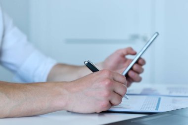 Müdür akıllı telefondaki istatistikleri kontrol ediyor. Ofis işi ve finans konsepti. Kapat.