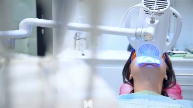 Professional Bleaching Procedure In Modern Dental Clinic. Woman In Protective Red Glasses While Laser Whitening. Dental And Teeth Healthcare Concept