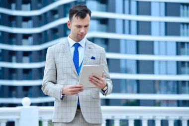 Takım elbiseli genç işadamı dijital tablet bilgisayar kullanıyor. İş ve bilgi teknolojisi kavramı.