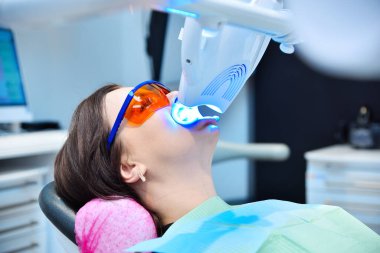 Koruyucu gözlüklü hastaya diş beyazlatma. Modern klinikte diş beyazlatıcı lazer. Diş hekiminde dişlerin beyazlaması.