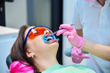 Kadın dişçi hastayı diş beyazlatma prosedürüne hazırlıyor. Diş ve diş beyazlatma kavramı.