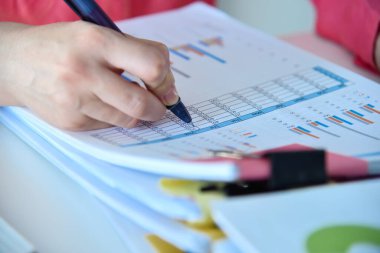 Kalemle çalışan muhasebeci kadın, mali analizlerde bir yıl boyunca düzeltir. Finansal ve evrak işleri. Kapat.