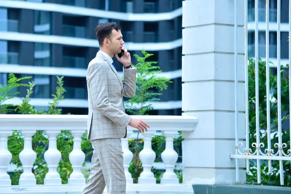 Young Businessman Walking Suit Talking Mobile Phone Skyscraper Background Business — Stockfoto